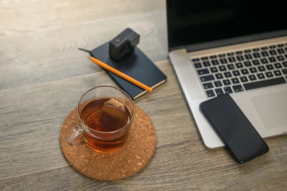 taza de té en la oficina, al lado de un portátil