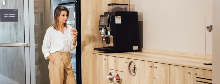 persona haciendo una pausa para el cafe junto a una maquina superautomatica