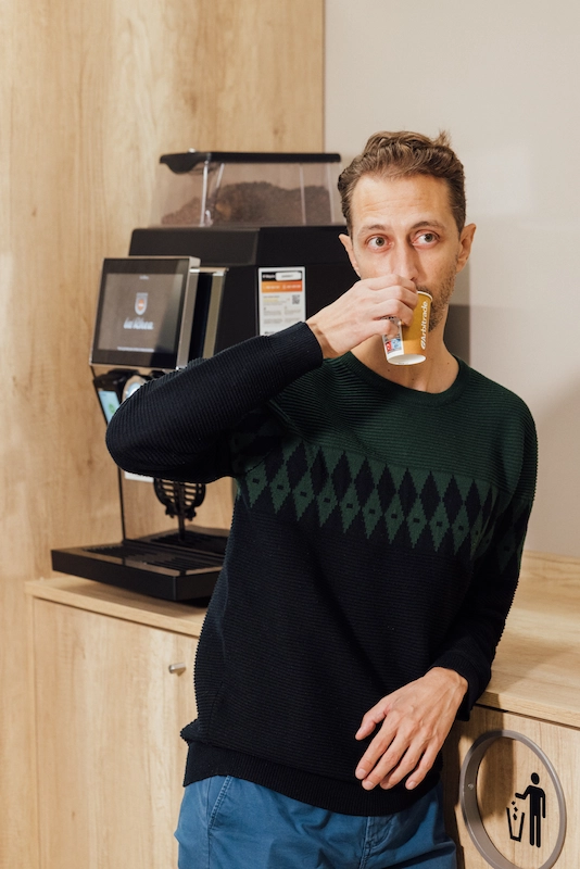 Serendipia en la oficina: Por qué las mejores ideas surgen frente a la máquina de café 1 persona tomando un café tranquilamente junto a la máquina de café automática de la oficina