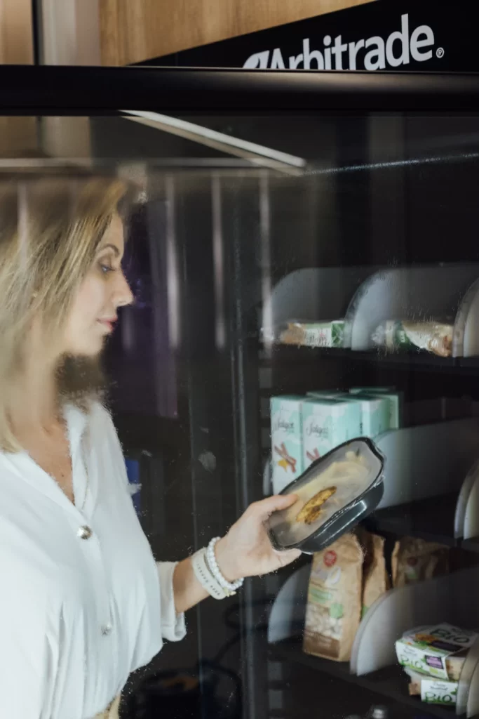 Empleada seleccionando un plato preparado en un micromarket 24/7 dentro de una empresa.