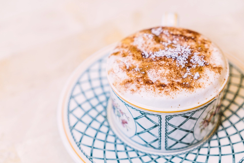 Taza de café con leche espolvoreado con canela y vainilla